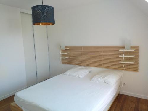 a bedroom with a white bed with a wooden headboard at LA ROLANDE in Penmarch