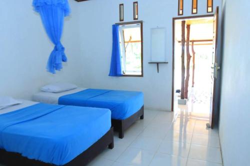 a blue room with two beds and a door at Arthur Homestay Telescope Mentawai in Tuapejat