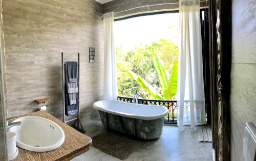 a bathroom with a large tub and a window at Puri Kasih Gottlieb in Ubud