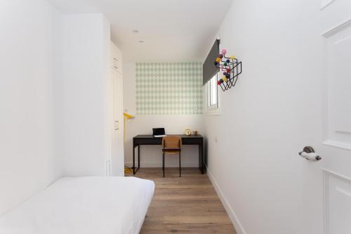 a bedroom with a desk and a table with a laptop at Casa Cosi - Atico in Barcelona
