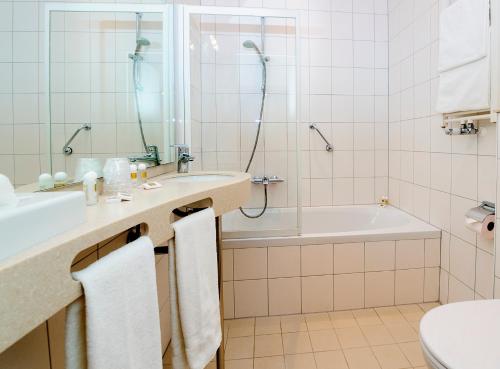 a bathroom with a tub and a sink and a toilet at Boulevard Hotel Scheveningen in Scheveningen