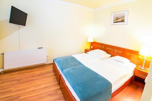 a bedroom with a bed and a flat screen tv at Hotel Silver in Hajdúszoboszló