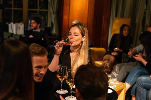 a woman drinking a glass of wine in a restaurant at Parkhotel Laurin in Bolzano