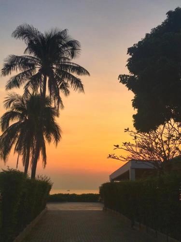 a sunset with two palm trees and a building at Rain condo ChaAm HuaHin by AY B311 in Cha Am
