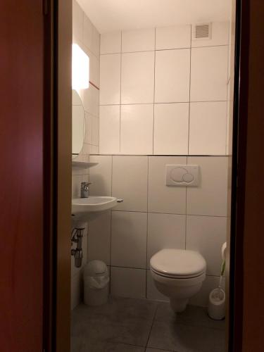 a white bathroom with a toilet and a sink at Zum Winzermännle in Würzburg