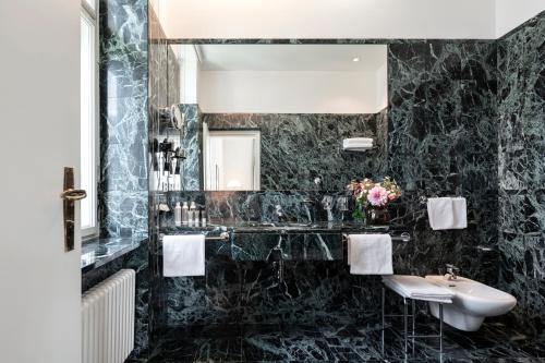 a black marble bathroom with a sink and a mirror at Parkhotel Laurin in Bolzano