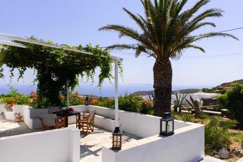 a palm tree on a white wall with a table and chairs at Arhontou in Apollonia