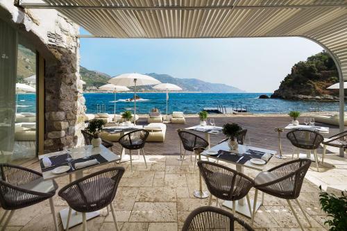 a patio with tables and chairs and a view of the ocean at Atlantis Bay - VRetreats in Taormina