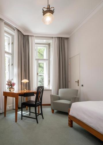 a bedroom with a bed and a desk and a chair at Parkhotel Laurin in Bolzano
