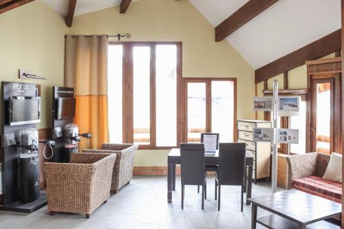 - une salle à manger avec une table, des chaises et des fenêtres dans l'établissement Residence Les Terrasses d'Azur - maeva Home, à Isola 2000
