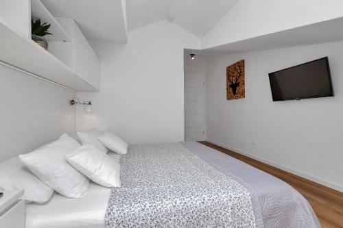 a white bedroom with a bed with a tv on the wall at Villa Sukara in Makarska