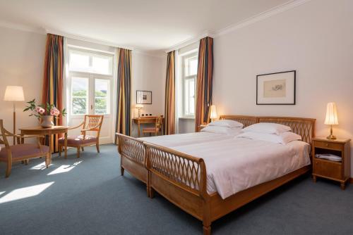 um quarto com uma cama grande, uma mesa e cadeiras em Parkhotel Laurin em Bolzano