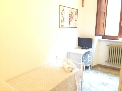 1 dormitorio con 1 cama y escritorio con TV en HostelCiompi en Siena