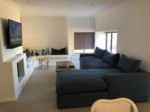 a living room with a blue couch and a tv at The Sanctuary Penthouse in Plettenberg Bay