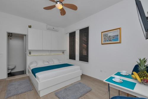 a white bedroom with a bed and a ceiling fan at Villa Sukara in Makarska