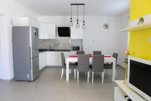Una cocina y un comedor con una mesa y sillas blancas. en Apartman Diva, en Orebić