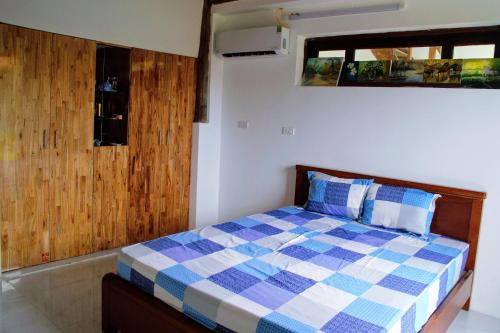 a bedroom with a bed with a blue and white checkered blanket at CocoPalm Villa near Beach - Coco Room in Hội Mỹ