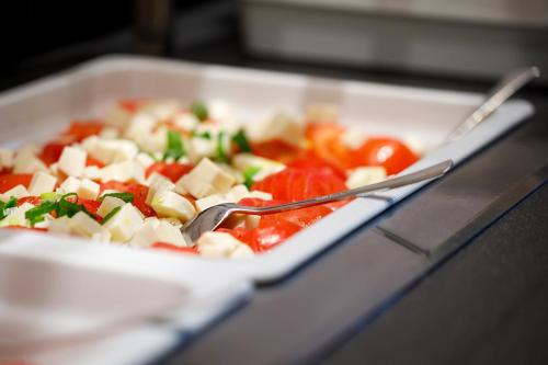 a plate of vegetables with a fork and knife at Hotel Allegra Lodge in Kloten