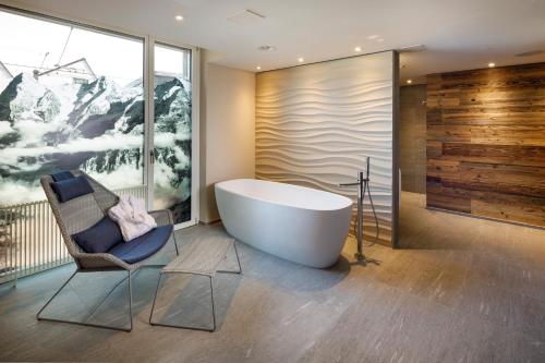 a bathroom with a bath tub and a chair at Hotel Allegra Lodge in Kloten