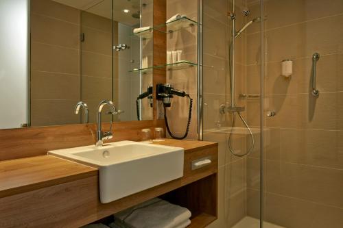 a bathroom with a sink and a shower at H4 Hotel München Messe in Munich