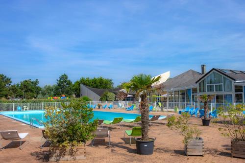 un complexe avec une piscine, des chaises et une maison dans l'établissement VTF Le Sénéquet, à Blainville-sur-Mer