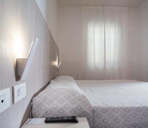 a small bedroom with a bed and a remote control on a table at Alfa Fiera Hotel in Vicenza