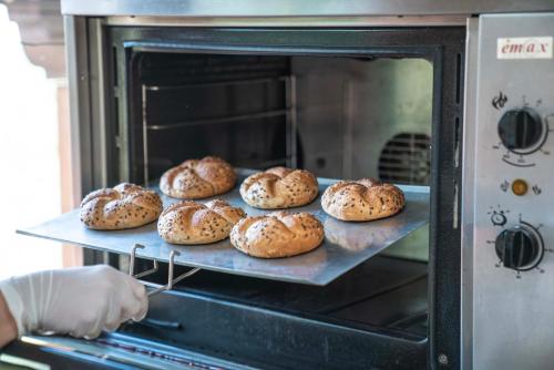 a person holding a tray of bagels in an oven at Hotel Szent István in Eger