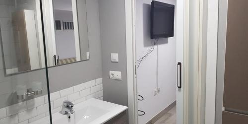 łazienka z umywalką, lustrem i telewizorem w obiekcie Apartamento Calarreona w mieście Águilas