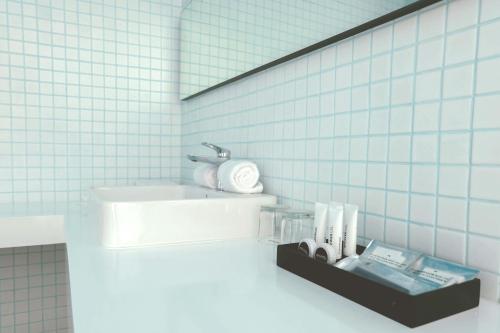 a bathroom with a sink and a shelf with toiletries at ARTOTEL Gajahmada Semarang in Semarang