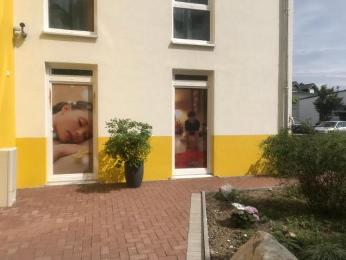 a yellow and white building with a poster of a girl at i-Motel in Obertshausen