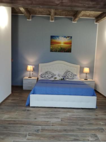 a bedroom with a bed with blue sheets and two lamps at Agriturismo Tenuta Villa Catena in Paglieta