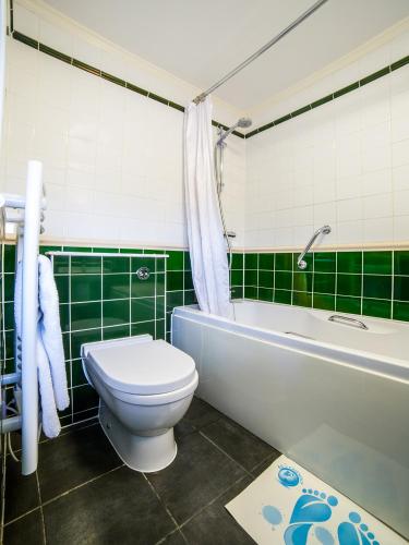 a green and white bathroom with a toilet and a tub at The Continental Hotel, Derby in Derby