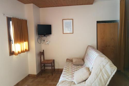 a living room with a white couch and a television at Le Serre Grou studioLarge studio at the gateway to the Ecrins National Park in Villar-dʼArène