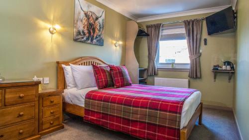 a bedroom with a bed with a plaid blanket at Eildon Guest House in Inverness