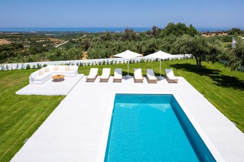 una piscina all'aperto con sedie a sdraio e una piscina di Vilana White Elegant Villa a Roúpai