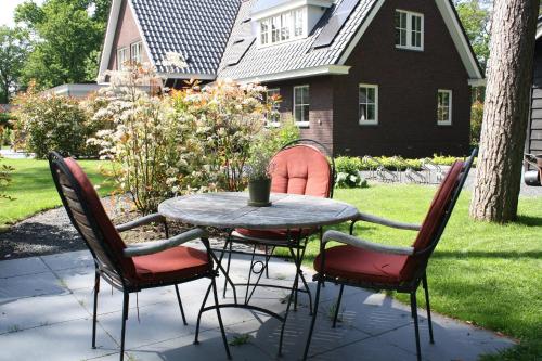 a patio table with four chairs and a table and a house at Bed & Breakfast Op 't Leven in Ermelo