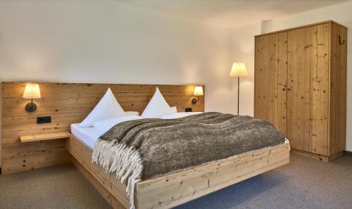 - une chambre avec un grand lit et une tête de lit en bois dans l'établissement BEIM MOSER Apartments, à Grän