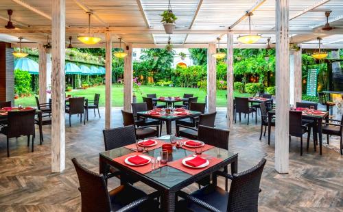 a restaurant with tables and chairs and a lawn at Kenilworth Hotel, Kolkata in Kolkata