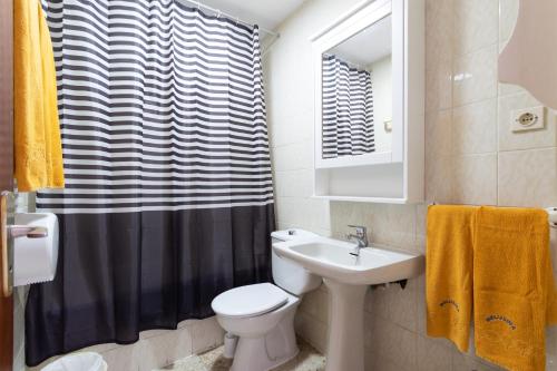 La salle de bains est pourvue d'un lavabo, de toilettes et d'un rideau de douche. dans l'établissement Apartamentos Melusina en Playa del Inglés al lado de la playa y las Dunas de Maspalomas, à Playa del Ingles