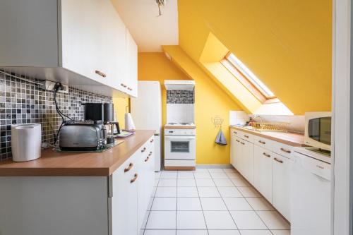 een keuken met witte kasten en gele muren bij le ciel d'opale in Wimereux