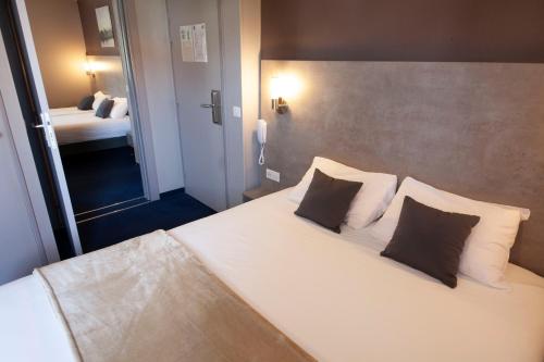a bedroom with a large white bed with two pillows at Hotel Lune Etoile in Clermont-Ferrand