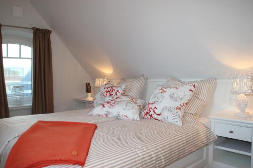 Schlafzimmer mit einem Bett mit roten und weißen Kissen in der Unterkunft Sylt Flair 9 in Westerland