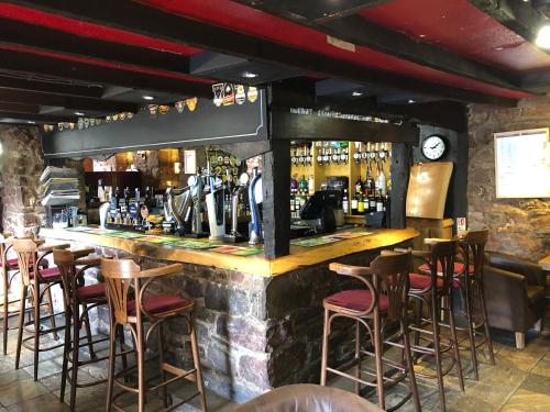 a bar with stools in a room with alcohol at Butchers Arms in Coleford