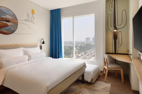 um quarto com uma cama grande e uma janela grande em ibis Styles Jakarta Simatupang em Jakarta
