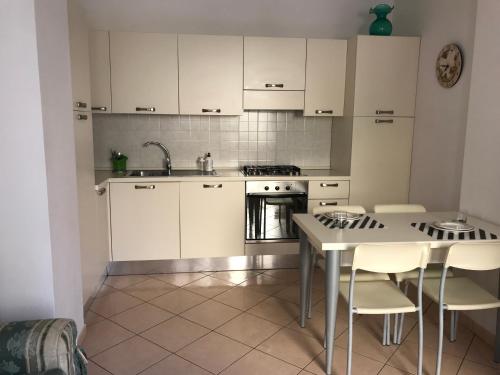 una cucina con armadi bianchi e tavolo con sedie di Casavacanze estate 3 a San Benedetto del Tronto