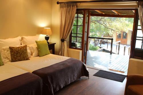 a bedroom with a bed and a sliding glass door at Tuskers Bush Lodge B&B in Hartbeespoort
