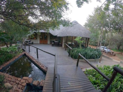 a wooden walkway leading to a house with a pond at Tuskers Bush Lodge B&B in Hartbeespoort