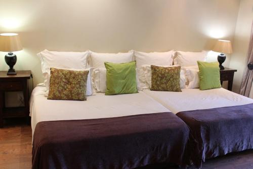 a bedroom with a large bed with green and white pillows at Tuskers Bush Lodge B&B in Hartbeespoort