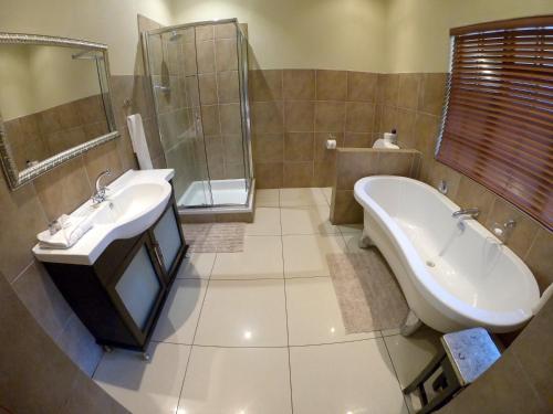 a bathroom with a tub and a sink and a bath tub at Tuskers Bush Lodge B&B in Hartbeespoort