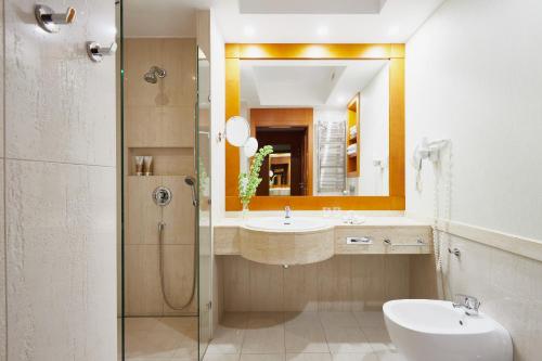 bagno con lavandino, doccia e specchio di Hotel SPA Dr Irena Eris Wzgórza Dylewskie a Wysoka Wieś
